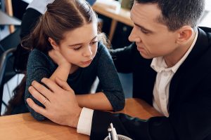 Cute girl closes ears when parents quarrel in lawyer office. Girl parents are getting divorced. Dissolution of marriage of two adults.