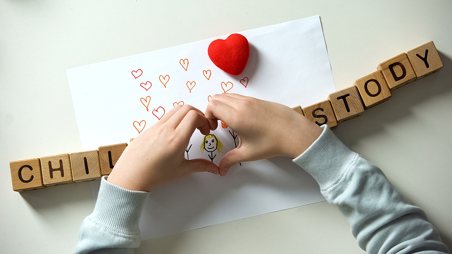 Child custody phrase and heart sign made from hands on family painting.