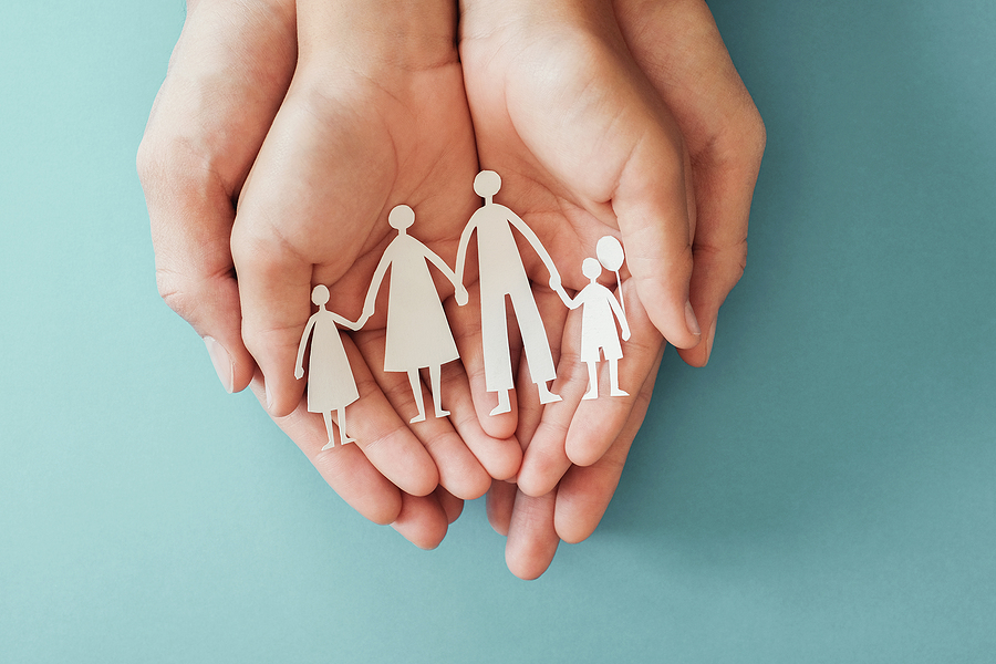 Adult and children hands holding paper family cutout, family home, child support concept.