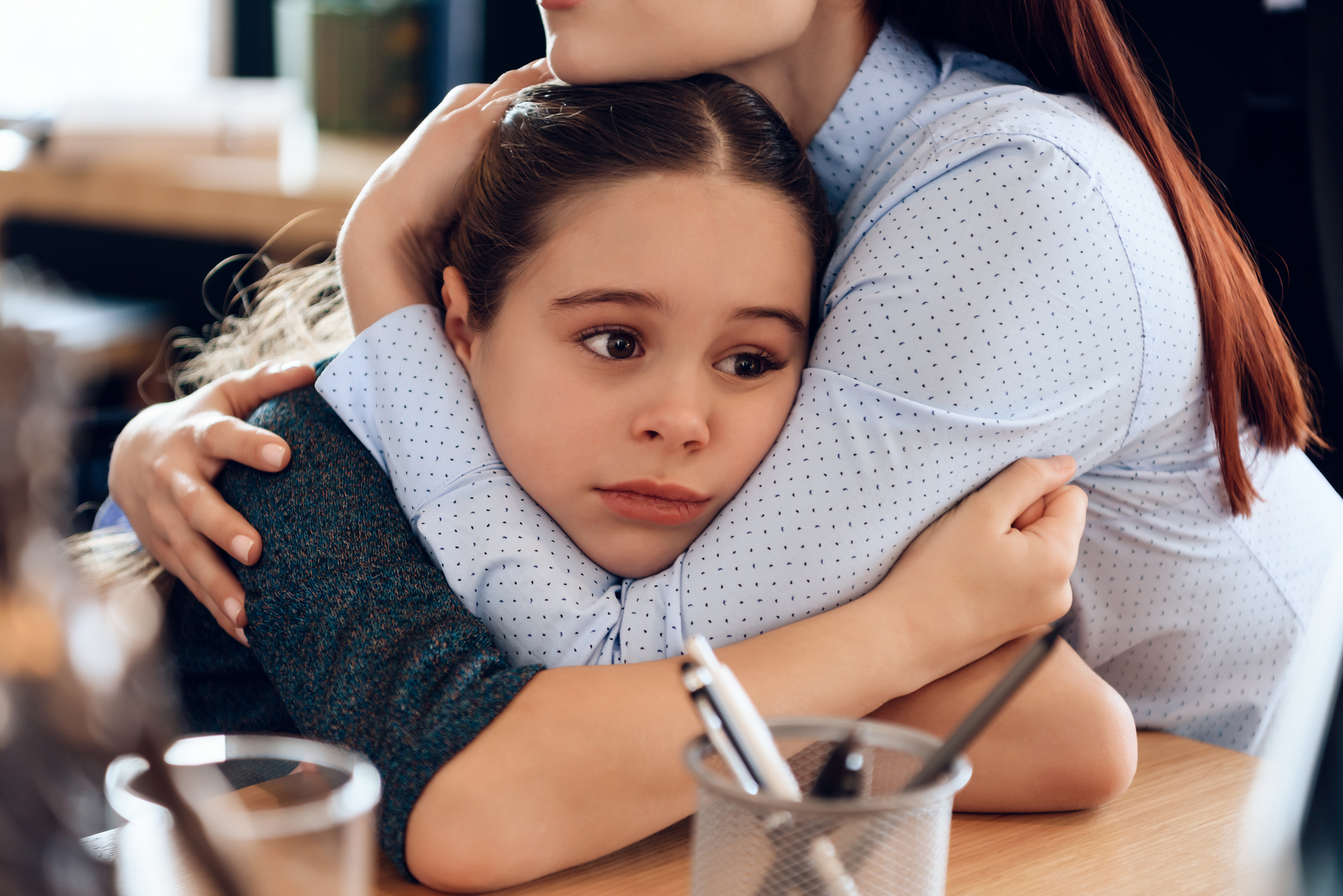 Mom hugging sad daughter.