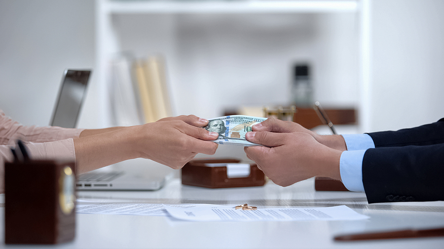 Male and female hands pulling money, dividing marital property during divorce.