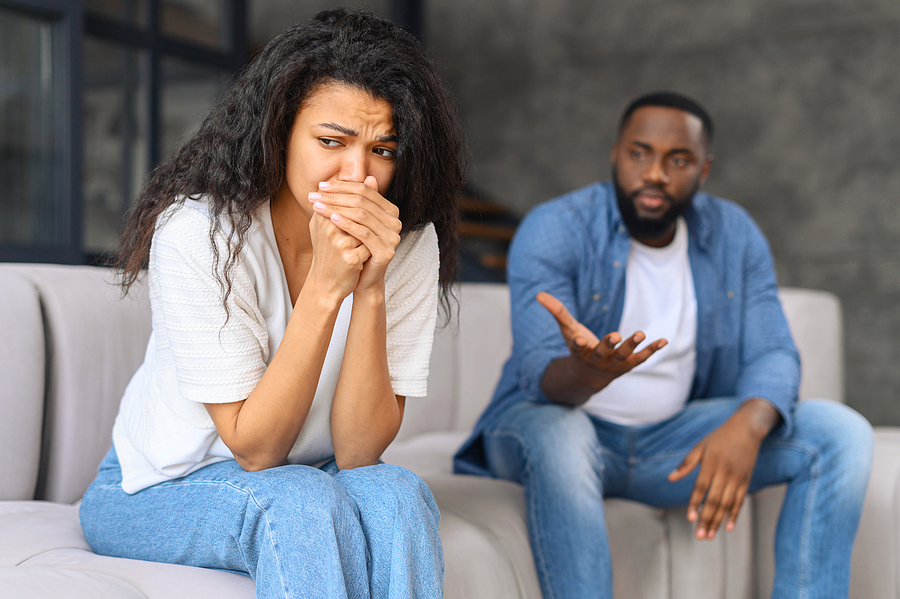 Divorcing couple arguing. Wife is sitting next to husband crying.