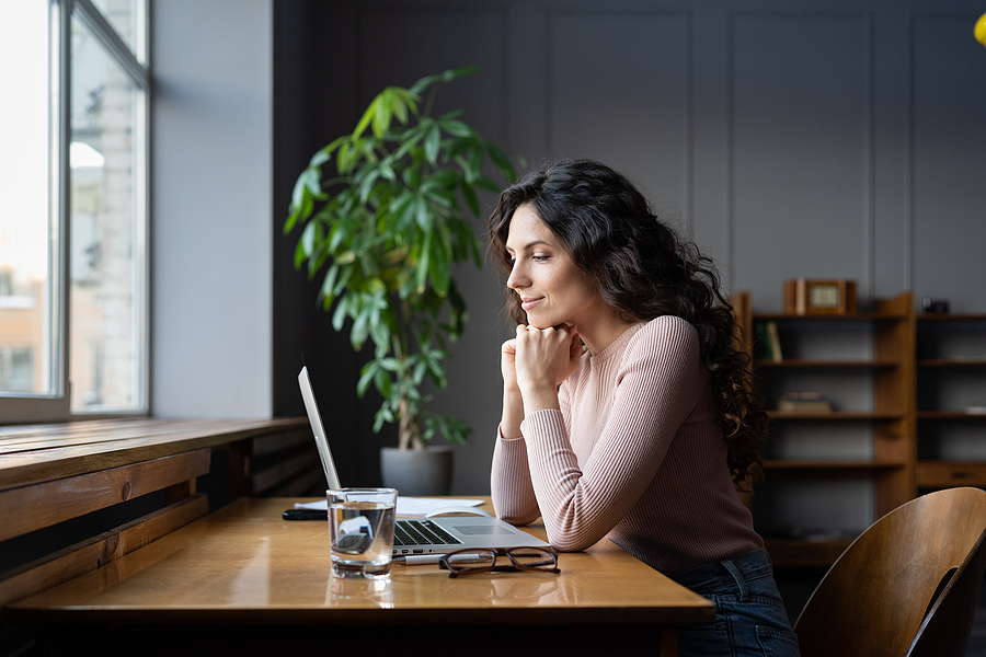 Single woman sitting at a desk looking at a computer.