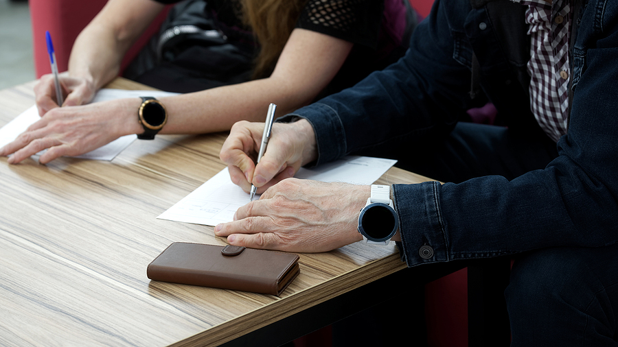 Adult man and woman fill out the forms. Concept of divorce proceedings, signing a marriage contract, lease agreement or notarized power of attorney. No face. Close-up