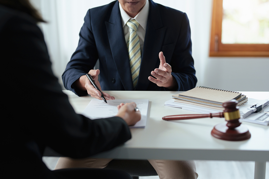 Lawyer holding a pen consulting with a client, gavel and papers on the table