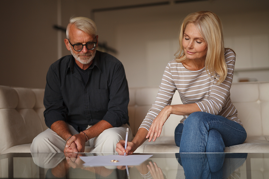 couple sitting on couch signing divorce papers