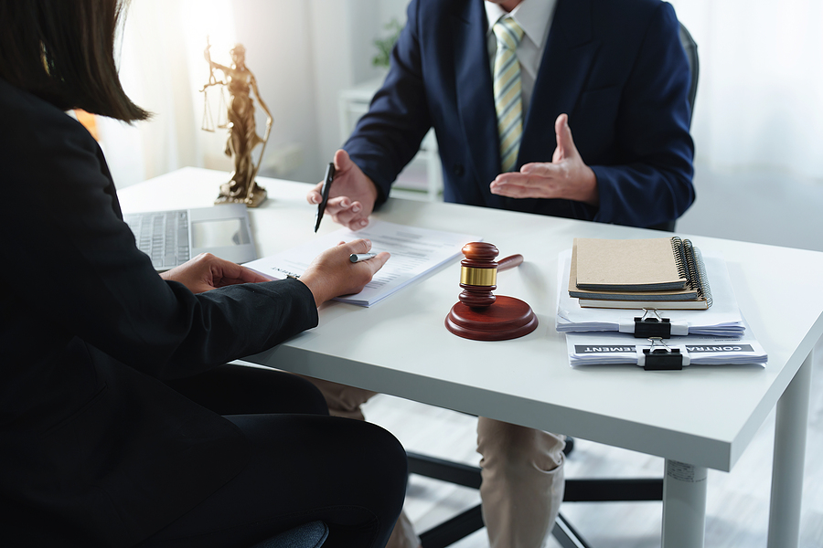 Lawyer sitting with a client at a desk with papers and gavel 