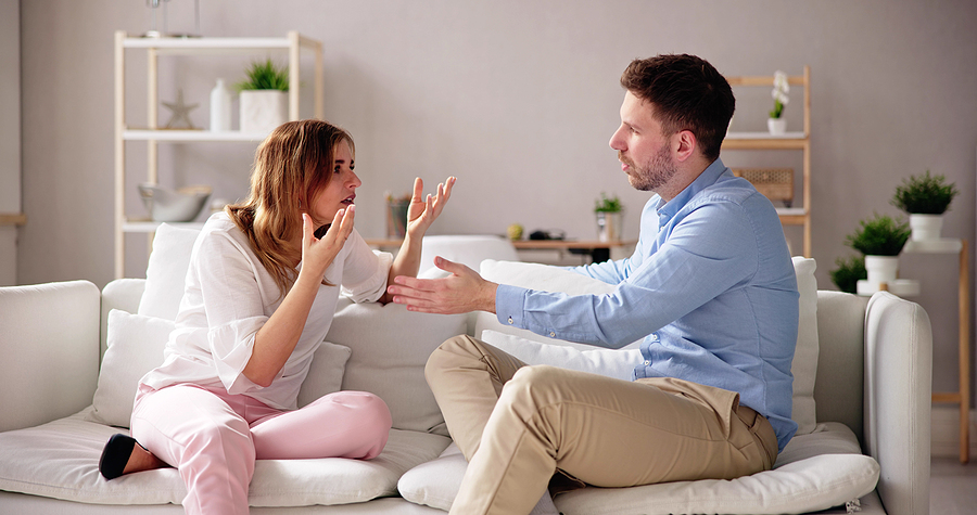 Man and woman arguing while sitting on a couch, dealing with high-conflict divorce