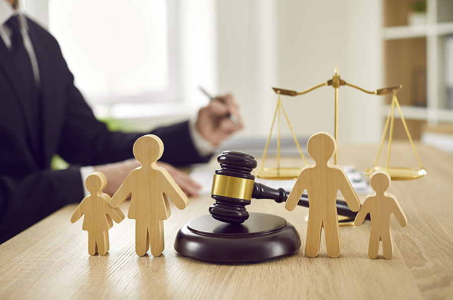 gavel on lawyers desk with wooden figures of a family - child support lawyer in the background