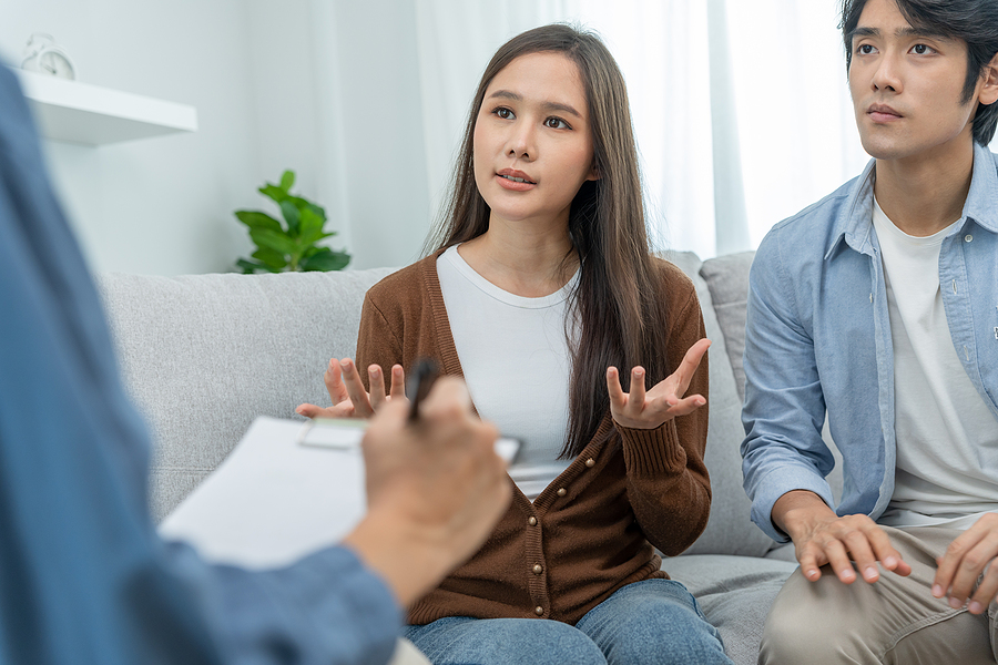 Couple speaking with person holding clipboard in office