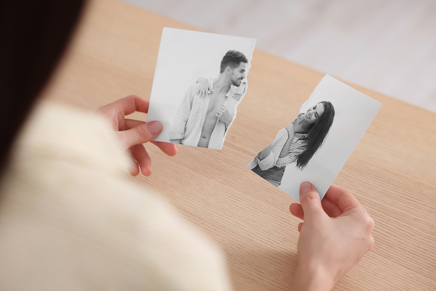 Divorce and breakup. Woman holding parts of ripped black and white photo.