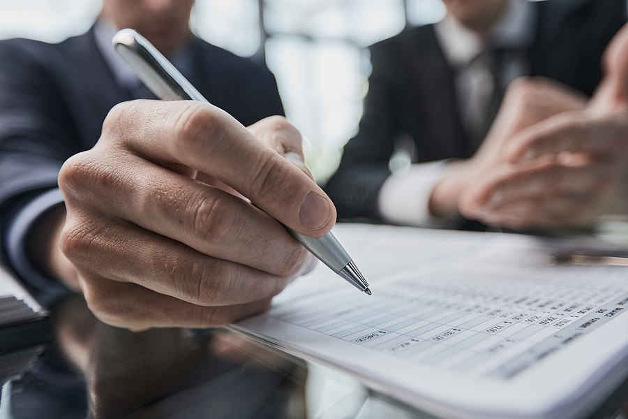 Close-up. Businessman looking at financial report and making notes with a pen in it