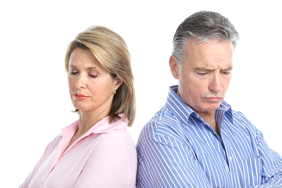Sad older couple facing away from each other against a white background. 