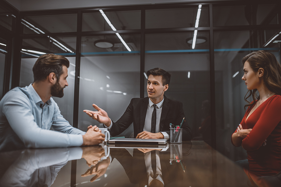 Man and woman meeting with an attorney in an office setting, sitting across from each other. 