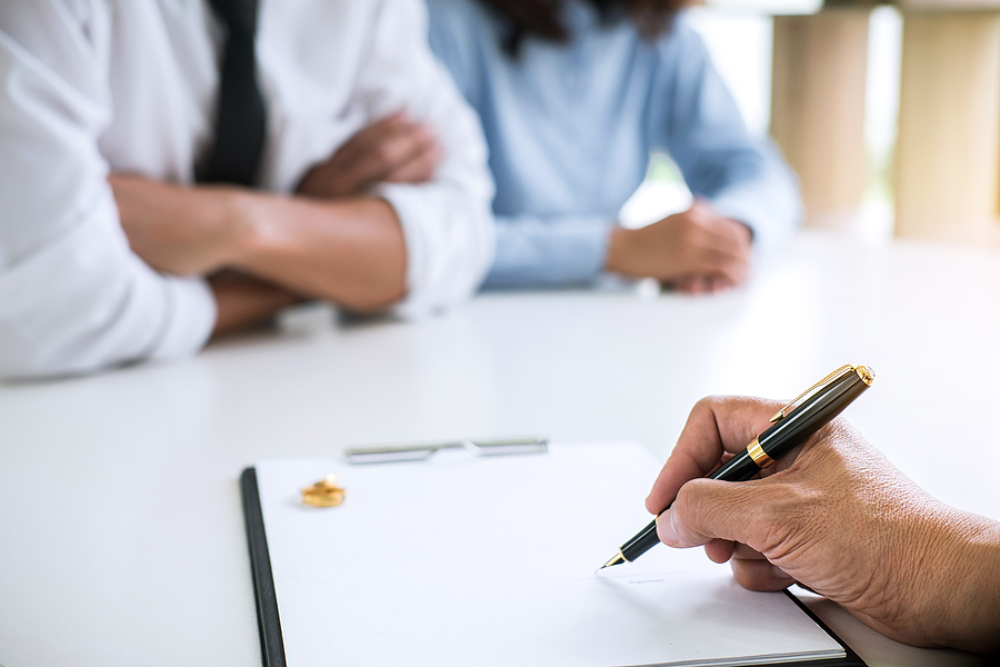 Closeup of a couple sitting in front of an attorney, preparing documents. 