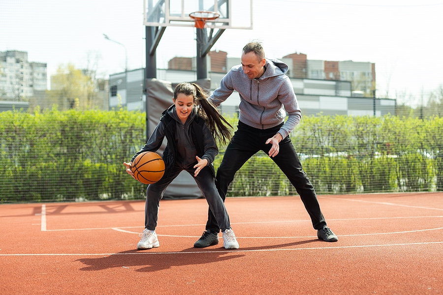 Father and teen playing basketball outside