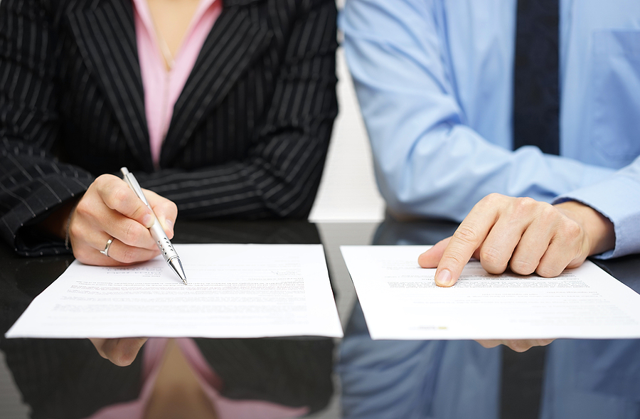 Closeup of a businessman and businesswoman inspecting contract in suits